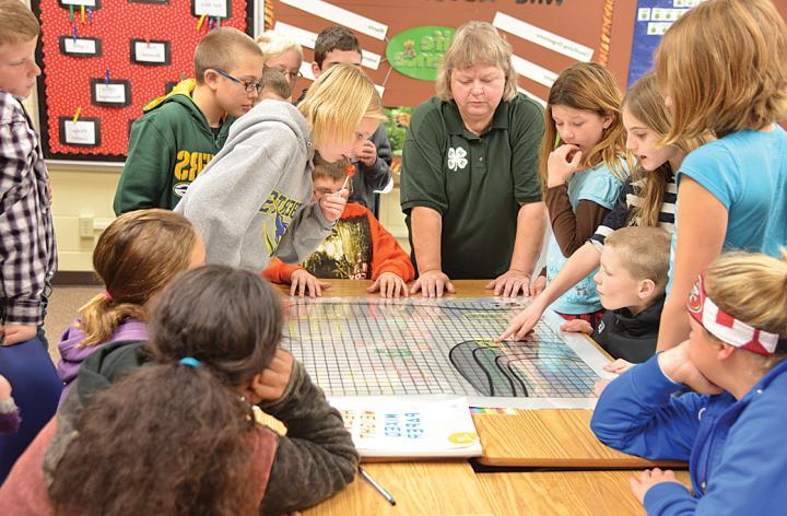 A 4-H volunteer leads a group of kids through a science experiment.